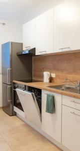 una cucina con armadi bianchi e frigorifero in acciaio inossidabile di Pal's Favoriten Apartment a Vienna