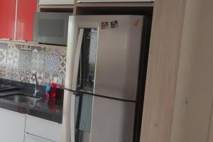 um frigorífico branco numa cozinha ao lado de um lavatório em Apartamento Lindo e Confortável com 2 quartos e estacionamento grátis Curitiba em Curitiba
