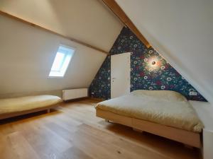 1 dormitorio en el ático con cama y ventana en Nachtegael Zomerhuis, idyllische woning in de Vlaamse Ardennen en Kluisbergen