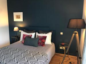 sypialnia z łóżkiem z poduszkami i niebieską ścianą w obiekcie La Mulonniere w mieście Saint-Sébastien-sur-Loire