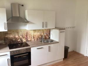 a kitchen with white cabinets and a sink and a stove at Haus Lies in Rehfelde