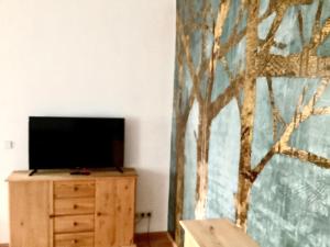 uma televisão numa cómoda numa sala com uma pintura em Haus Lies em Rehfelde