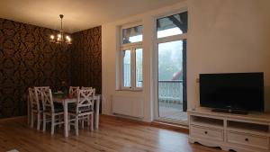 ein Wohnzimmer mit einem Tisch und einem Flachbild-TV in der Unterkunft Ferienwohnung zur Silbertanne in Ilsenburg