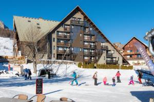 a group of people skiing in the snow in front of a building at Appartement Chabrières in Réallon