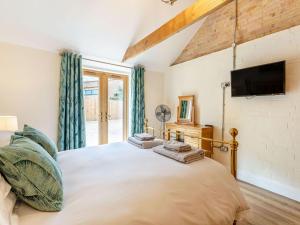 a bedroom with a large bed and a tv at Tawny Acre Barn - Uk38614 in Wisbech