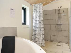 ein Badezimmer mit einer weißen Badewanne und einer Dusche in der Unterkunft 8 person holiday home in Ansager in Ansager