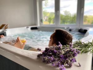 une femme dans une baignoire avec une boisson et des fleurs dans l'établissement APARTAMENTY Adamcykówka blisko Velo Czorsztyn, Velo Dunajec ! Jacuzzi i Sauna w cenie!, à Kluszkowce