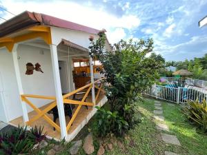 ein kleines Haus mit einer Veranda und einem Zaun in der Unterkunft Charmant bungalow avec piscine Kaz' Basse in Bouillante