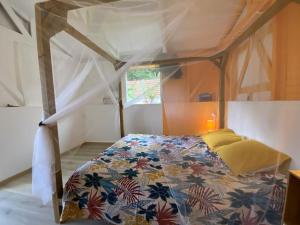 ein Schlafzimmer mit einem Himmelbett in einem Zimmer in der Unterkunft Charmant bungalow avec piscine Kaz' Basse in Bouillante