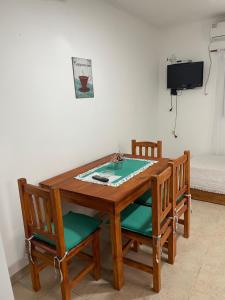 a wooden table with four chairs and a tv at Bungalows palmar in Chajarí