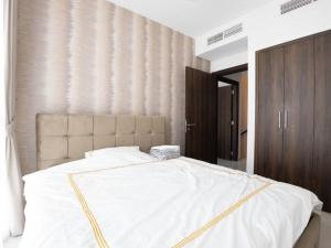 a bedroom with a large white bed with a headboard at Brand new luxury 3bedroom villa in Damac Hills 2 in Dubai