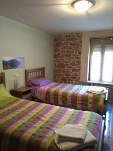 a bedroom with two beds and a stone wall at Casa rural Huertos de Sayago in Moralina