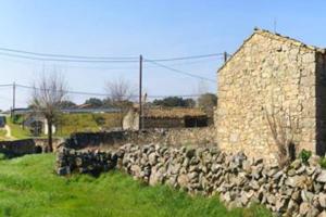 una pared de piedra junto a un edificio de piedra en Casa rural Huertos de Sayago, en Moralina