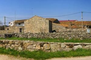 a stone wall in front of a stone building at Casa rural Huertos de Sayago in Moralina