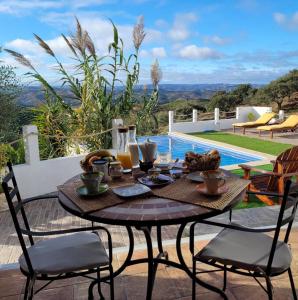 a table and chairs on a patio next to a pool at Varandas do Vale Furnazinhas in Castro Marim