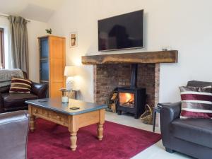 a living room with a fireplace with a tv above it at Holly Cottage Barn in Stoke Edith