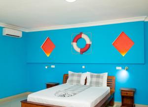 a bedroom with a blue wall and a bed at Amazone Hotel Tulear in Toliara