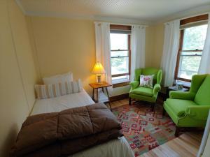 a bedroom with a bed and a green chair at Keene Valley Lodge in Keene Valley