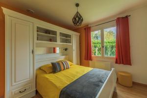 um quarto com uma cama amarela e uma janela em Belle maison rénovée, 5mn à pied de la mer, classée meublé de tourisme 3 étoiles em Île-Tudy