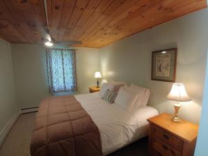 a bedroom with a large white bed with a wooden ceiling at Keene Valley Lodge in Keene Valley