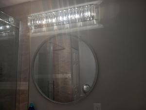 a bathroom with a round mirror with lights on the wall at Splendid Place in Kingston