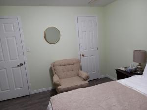 1 dormitorio con silla, cama y espejo en Splendid Place, en Kingston