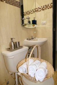 La salle de bains est pourvue de toilettes, d'un lavabo et d'un panier de serviettes. dans l'établissement Estudio D2 Riocentro Norte-Mall Del Rio Samanes, à Guayaquil