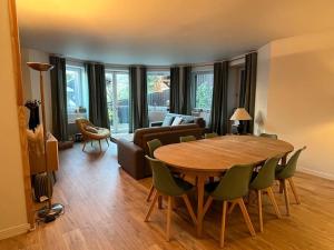 - un salon avec une table en bois et des chaises vertes dans l'établissement Superbe appartement COURCHEVEL VILLAGE, à Courchevel