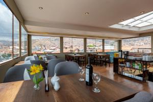 un restaurante con mesa, sillas y ventanas en Tikala Cusco Boutique Hotel, en Cusco