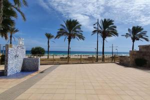 een park met palmbomen en het strand bij Relax en primera línea AP4 in El Campello