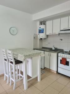 una cocina con mesa y algunos armarios blancos en Acogedor departamento 1 dormitorio en El Palomar