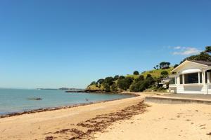 a beach with a house and the ocean at The Partchery Devonport in Auckland