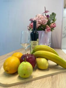 uma tábua de cortar madeira com frutas, copos de vinho e flores em Lovely Apartment em Tirana