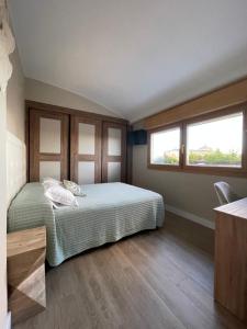 1 dormitorio con 1 cama y 2 ventanas en El Roble 9 en Astorga