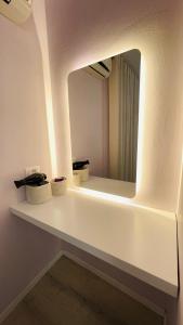 uma casa de banho com um espelho numa prateleira branca em Lovely Apartment em Tirana