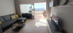 ein Wohnzimmer mit einem Sofa und einem TV in der Unterkunft Villas canarias con vista al mar in Adeje