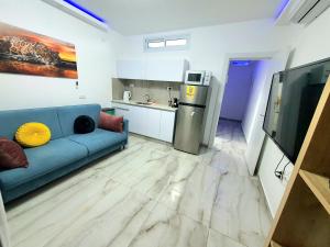 a living room with a blue couch and a kitchen at Barak Royal Suites VIP 94 - חמש דקות מהים ומהטיילת in Eilat