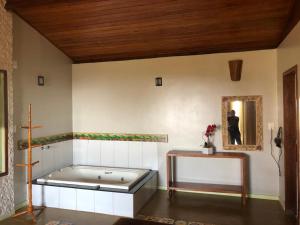 a bath tub in a room with a person in a mirror at Chalés Lavras de Minas - Canadá in Lavras Novas +25 photos