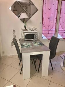 a dining room table with chairs and a microwave at Le carre des Musiciens CENTRE CANNES MER in Cannes