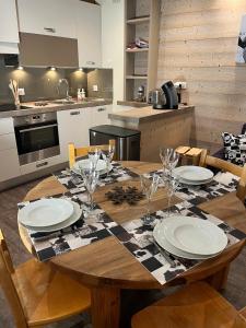 uma cozinha com uma mesa de madeira com pratos e copos de vinho em Tignes le Lac - Le Santon bel appartement 4 pers em Tignes