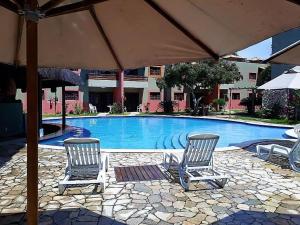 twee stoelen en een parasol naast een zwembad bij Triplex Tulipa - Praia da Pipa Centro in Pipa +22 foto's