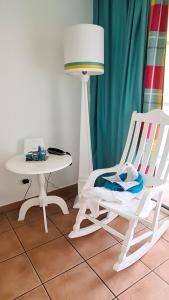 uma cadeira de balanço branca ao lado de uma mesa e de um candeeiro em Studio Premium Vue Mer, Plage em Sainte-Luce