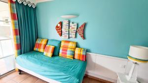 ein blaues Zimmer mit einer Couch mit bunten Kissen in der Unterkunft Studio Premium Vue Mer, Plage in Sainte-Luce