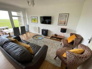 フレッシュウォーターにあるSEAVIEW self-catering coastal bungalow in rural West Wightのリビングルーム(黒い革張りのソファ、椅子付)