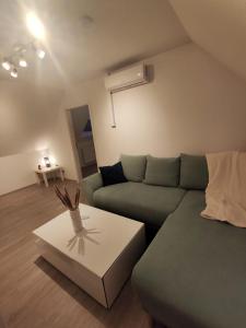 Dachgeschosswohnung mit Klimaanlage in bester Lage في مندن: غرفة معيشة مع أريكة خضراء وطاولة