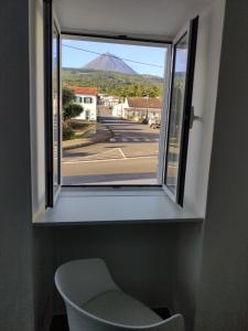 uma janela com uma cadeira e vista para uma montanha em Casa da Avó Biza em São Roque do Pico