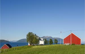 un granero rojo y blanco en una colina junto al agua en The Lighthouse Keepers House, en Røssneshamn