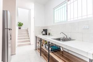 eine weiße Küche mit einem Waschbecken und einer Treppe in der Unterkunft Casa Familiar Sian Kaan in Caucel