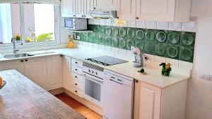 a kitchen with white cabinets and a green accent wall at Villa Calma Climatized pool Private Jacuzzi Spa in Tarajalejo in Tuineje