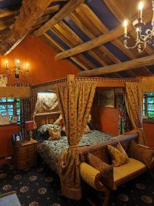 um quarto com uma cama de dossel, um sofá e uma cadeira. em Wizards Thatch Luxury Suites em Alderley Edge